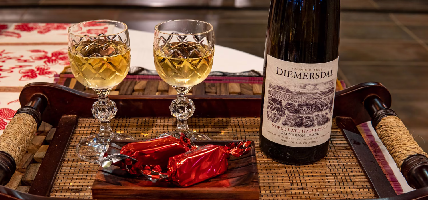 A bottle of Diemersdal and two glasses on a carved tray