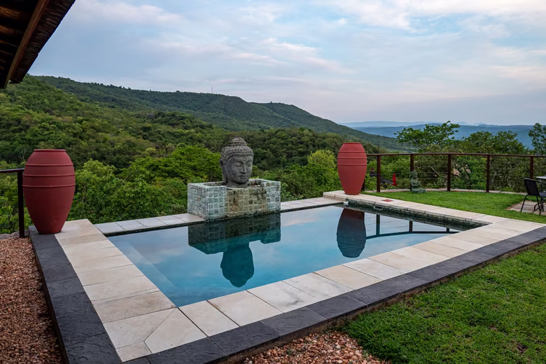 A stone Buddha above the pool, looking out over the hills