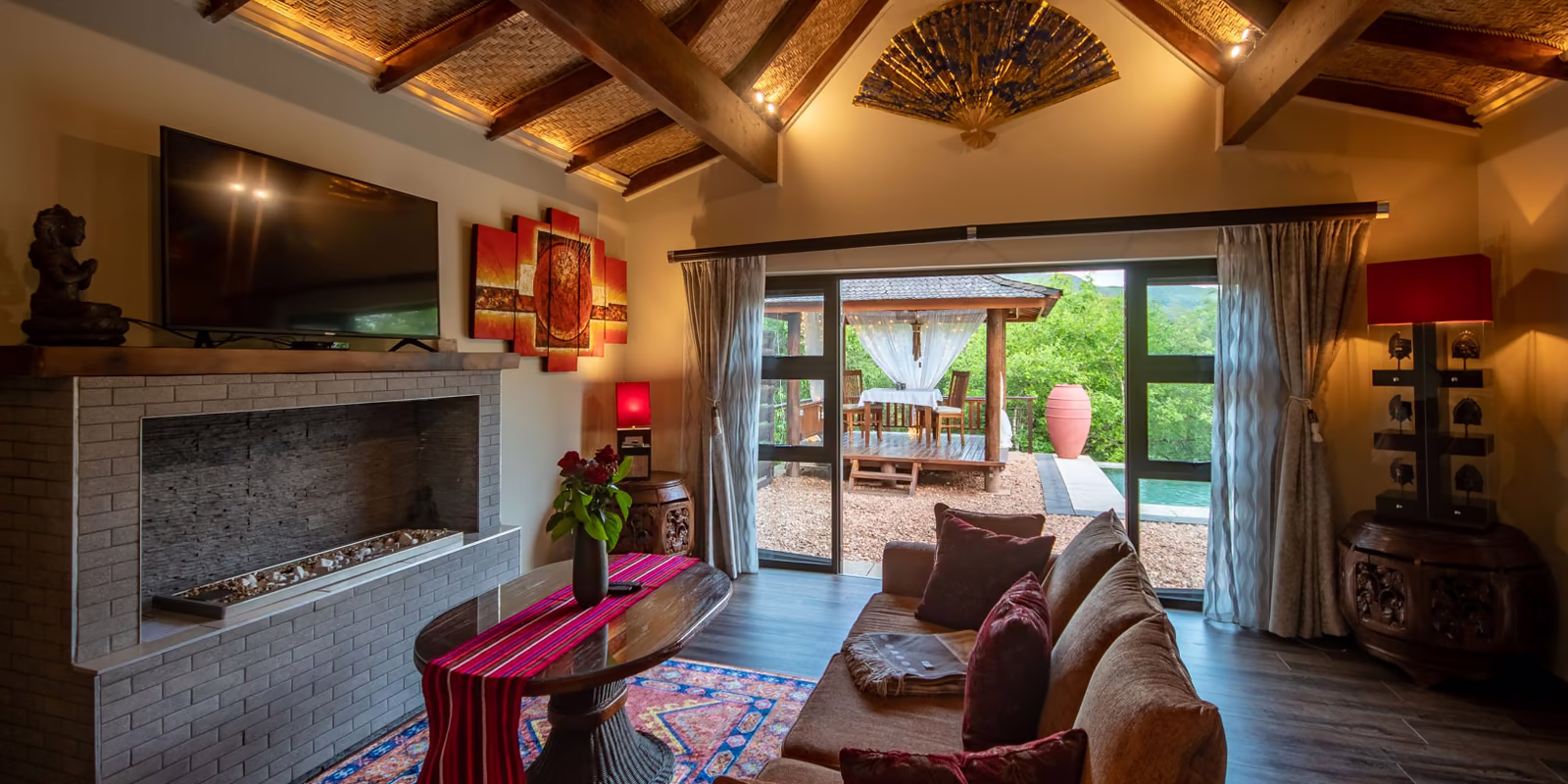 Villa lounge with its fireplace, opening onto the gazebo and pool