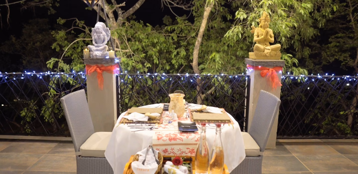 A table for two laid up in the garden at night, lit by fairy lights and lanterns